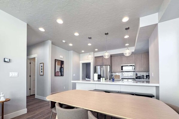 A modern kitchen with white countertops, stainless steel appliances, and recessed ceiling lighting.