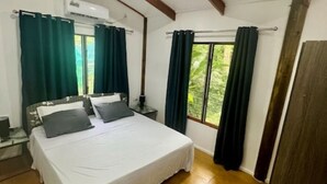 Une chambre à coucher avec un lit, des rideaux, un ventilateur de plafond et une fenêtre donnant sur un beau paysage.
