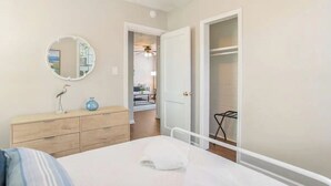 Een slaapkamer met een bed, een dressoir, een ronde spiegel en een inloopkast.