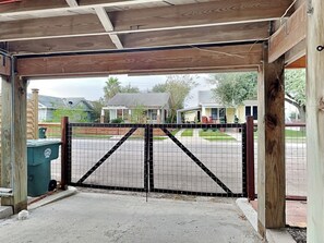 A gated entrance with a metal gate and wooden posts. - Treehouse Haven by Ryson Vacation Rentals (Galveston)