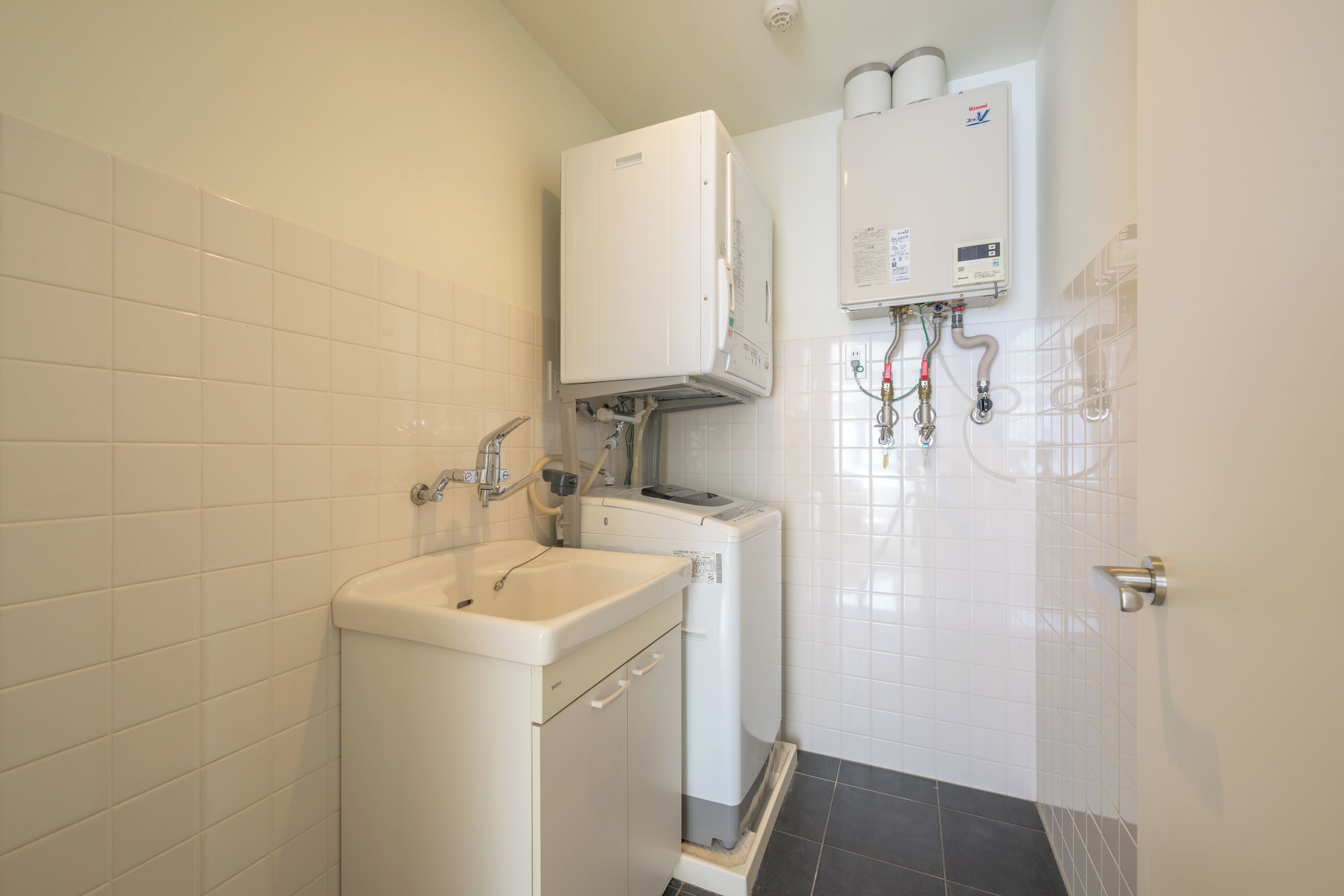 Et badeværelse med en hvid vask, toilet og en hvid vandvarmervandvarmervægmonteret.