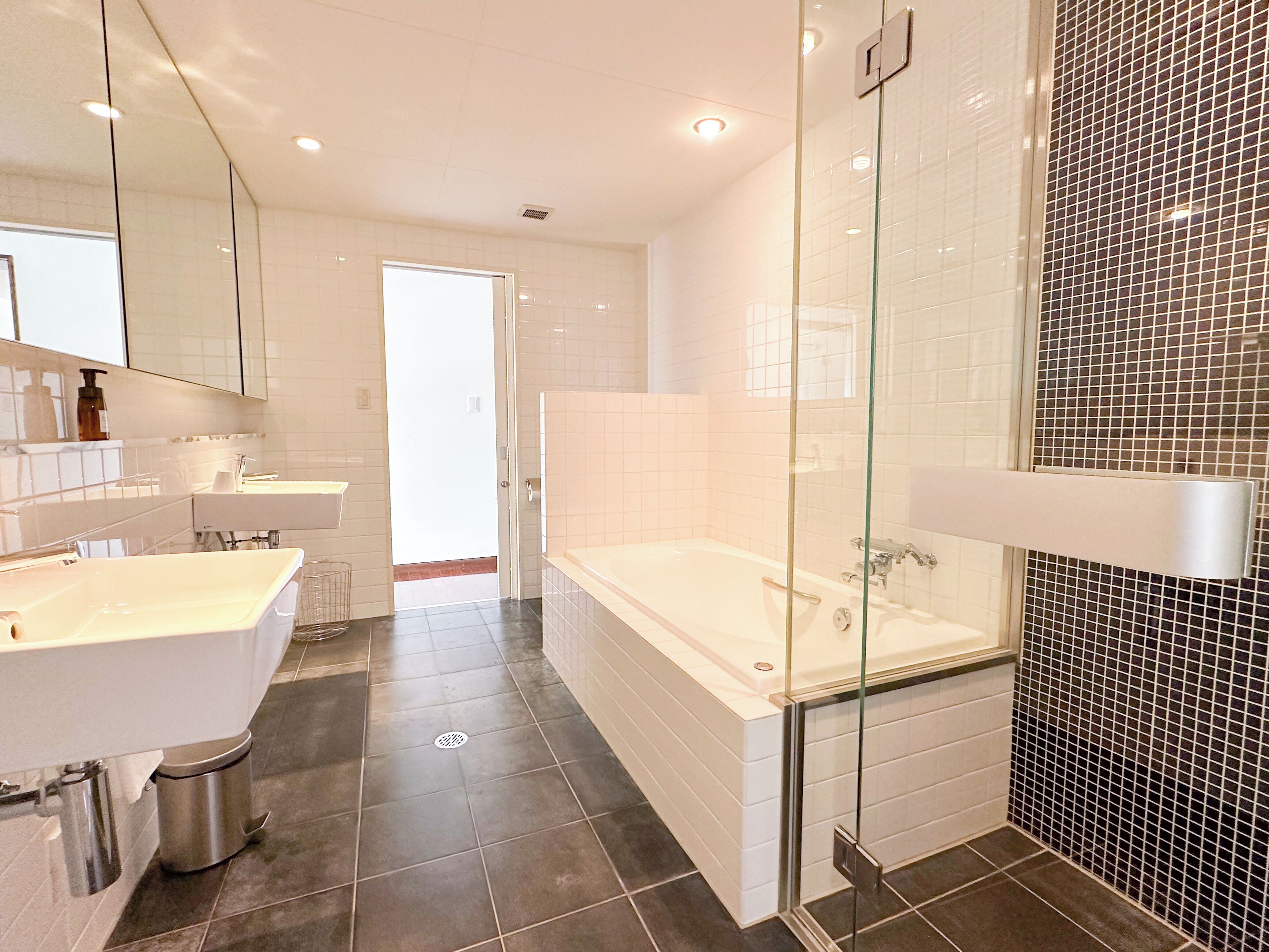 Un baño moderno con una bañera amplia, una zona de ducha separada y un tocador con espejo.