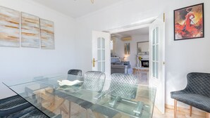 Un salon moderne avec une table à manger au plateau en verre, deux fauteuils rembourrés et un canapé.