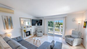 Un salon avec une cheminée, un canapé, une télévision et un balcon offrant une vue.