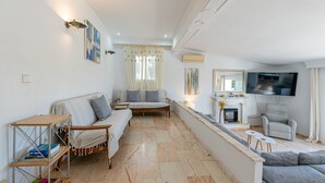 Un salon spacieux avec un canapé, des fauteuils, un téléviseur et une cheminée.