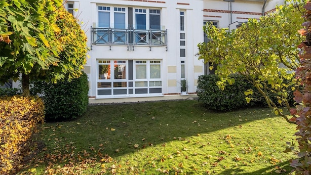 Un bâtiment à deux étages appelé « Villa Nicole », doté d’un balcon, de grandes fenêtres et d’une pelouse bien entretenue.