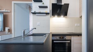 A modern kitchen with a black countertop, stainless steel appliances, and a built-in oven.