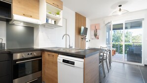 A modern kitchen with a built-in oven, dishwasher, and a large island with seating. - Magnificent villa with garden for 9 people (Sérignan)