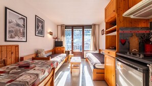 Une pièce confortable comprenant un lit, un canapé, une petite table, un téléviseur et un coin cuisine avec un réfrigérateur et des placards.