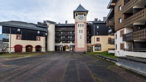 A building with a central tower, multiple balconies, and a paved courtyard. - Charming Appt 5 pers near the slopes (Morillon)