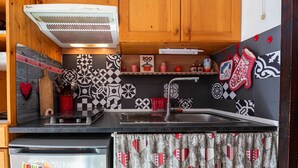 Une cuisine avec un dosseret à carreaux noirs et blancs, un évier en acier inoxydable et des armoires en bois.
