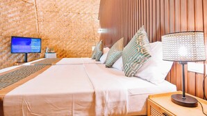 Habitación de hotel con una cama grande, un televisor sobre un soporte, una lámpara y un diseño tejido en la pared.