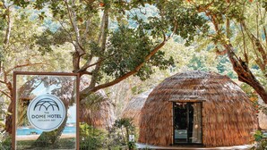 Estructura de techo de paja con un cartel que indica Hotel The Dome Bahía Caylanbe.