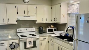 A kitchen with white cabinets, a stove, a microwave, and a refrigerator. - Charming 3-bedroom house with comfortable beds close to the beach! (Long Beach)