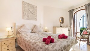 A bedroom with a bed, two bedside tables, a dresser, a chair, and a window with curtains. - Cozy home in Nerja with WiFi (Nerja)