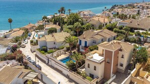A coastal residential area with Mediterranean-style buildings, a swimming pool, and a view of the sea. - Cozy home in Nerja with WiFi (Nerja)