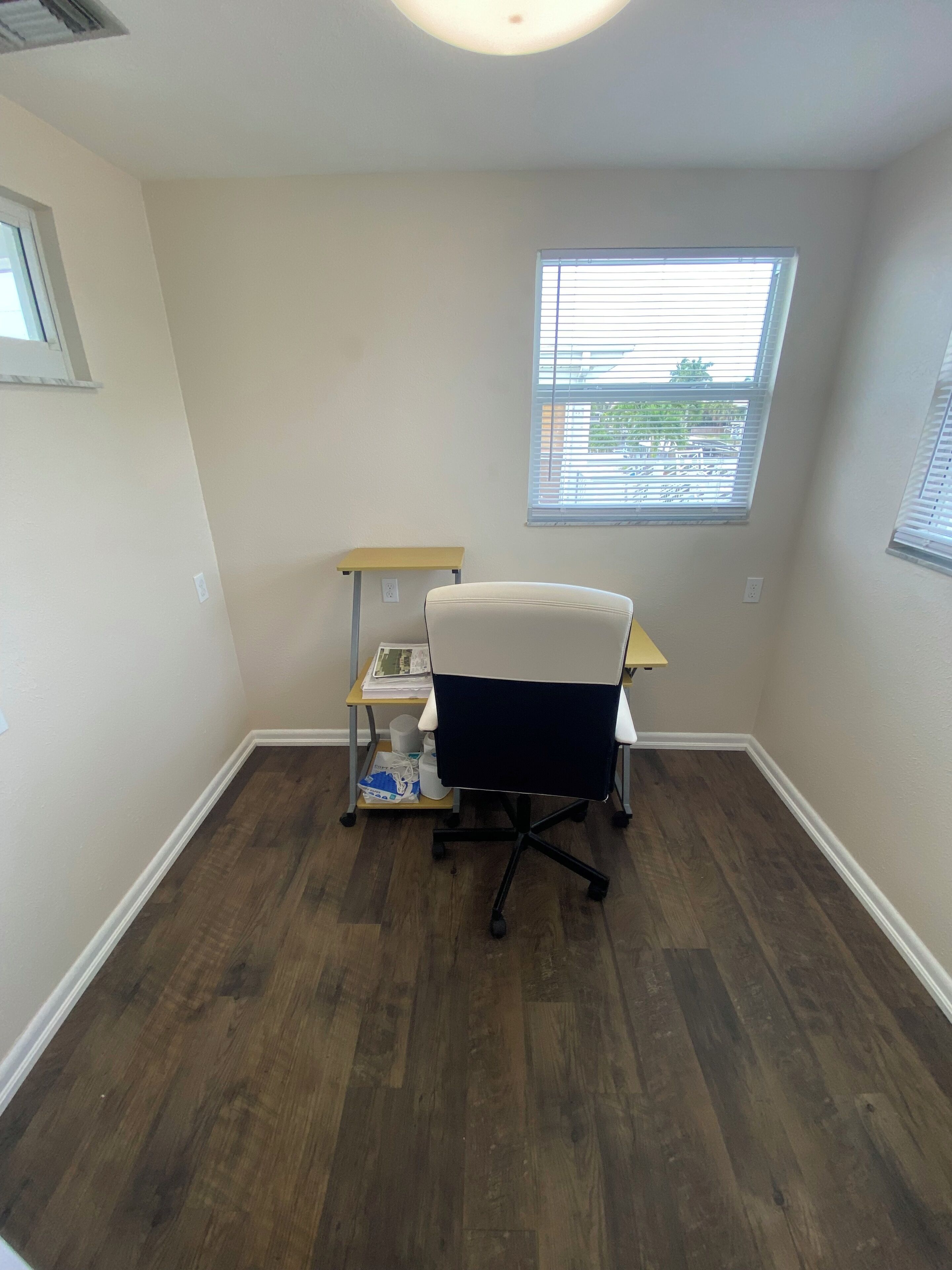 A small office space with a desk, chair, and a window with blinds.