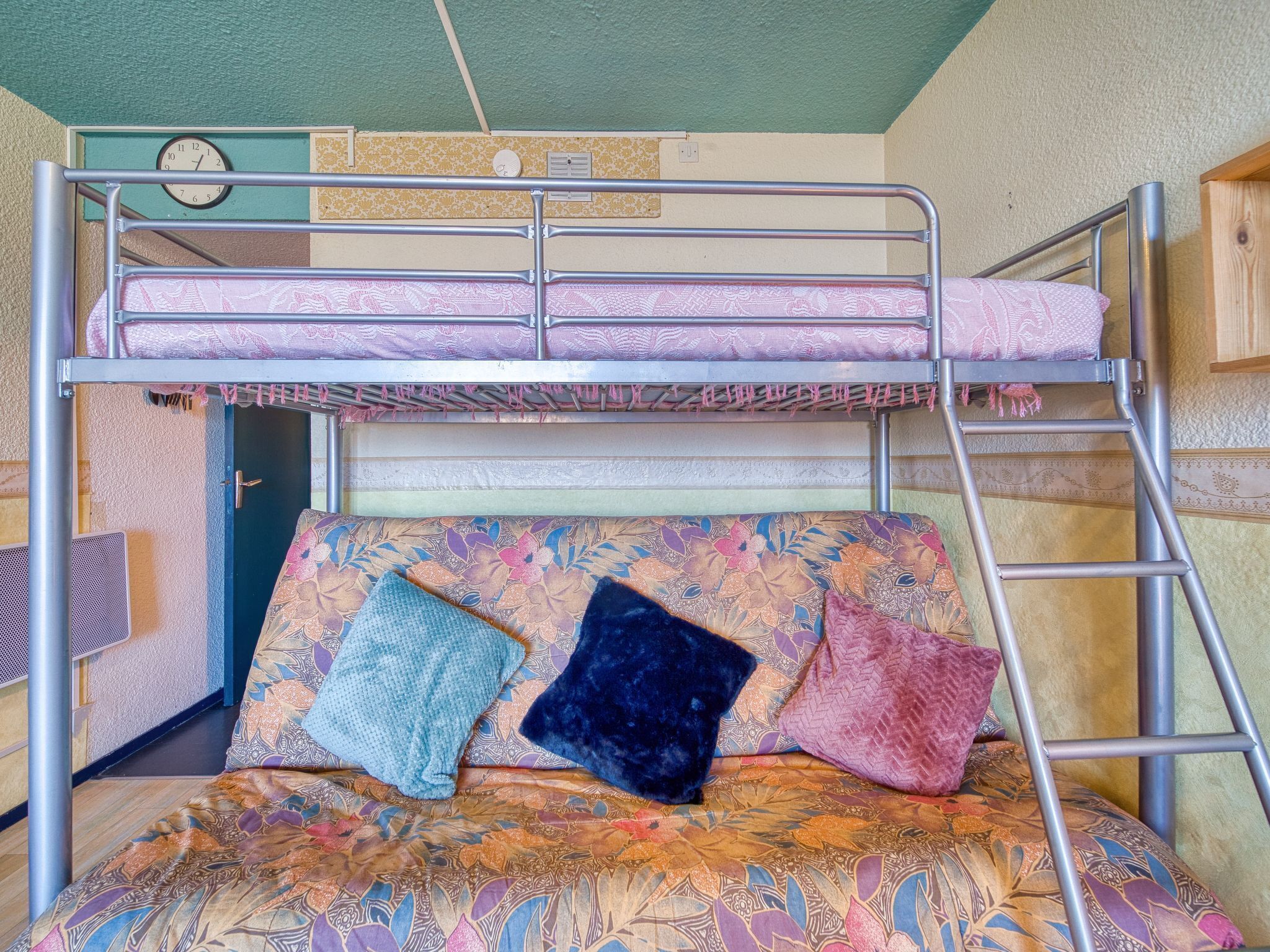 Ein Stockbett mit einer unteren Liege, einer Leiter und einer Matratze mit Blumenmuster.
