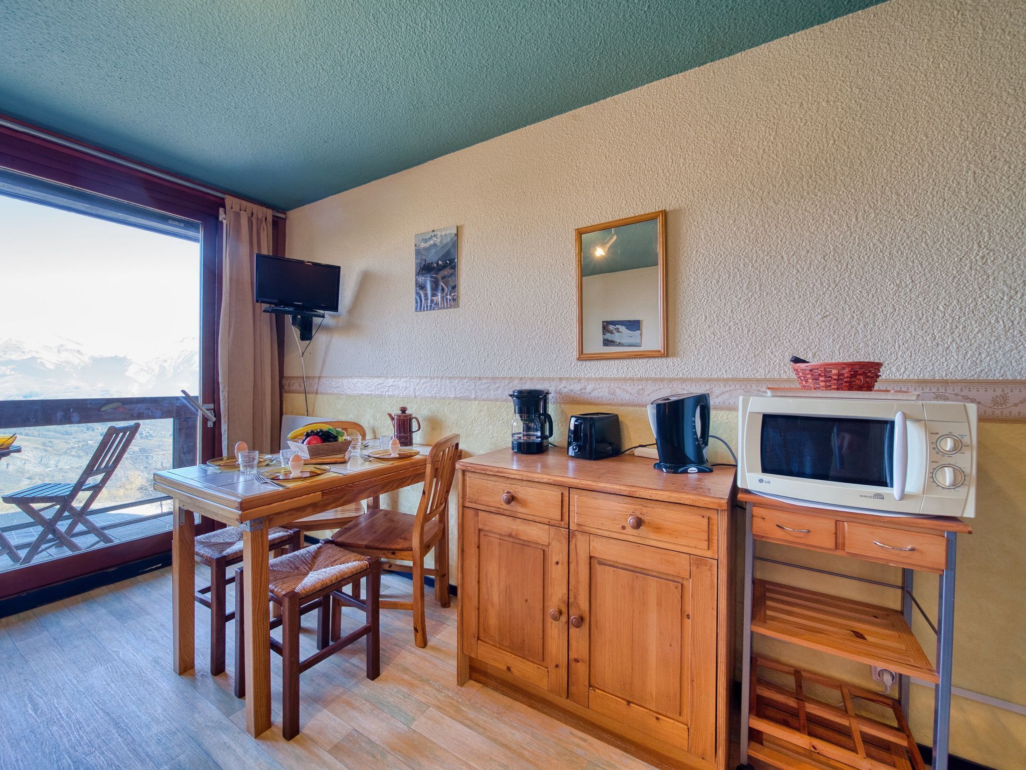 A cozy kitchen with wooden cabinets, a dining table, and chairs. A microwave and coffee maker are on the counter.