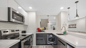 Una cocina moderna con electrodomésticos de acero inoxidable, horno empotrado y lavavajillas.