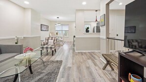 Una sala de estar moderna con una mesa de centro de vidrio, un sofá gris, un sillón escocés y un banco de madera.