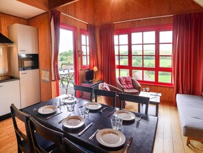 A dining area with a table set for four, a television, and a view of the outdoors.