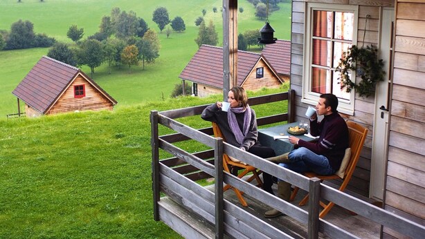 Una cabaña de madera con balcón que da a un paisaje verde.