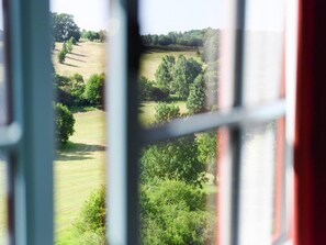 A view through a window with a grid pattern, overlooking a green landscape with trees and open fields. - Wooden Chalet in Abbeville Near Somme Bay (Grand-Laviers)
