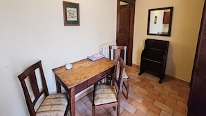 Een eethoek met een houten tafel en stoelen, een radiator, een lijst met een afbeelding en een spiegel aan de muur.