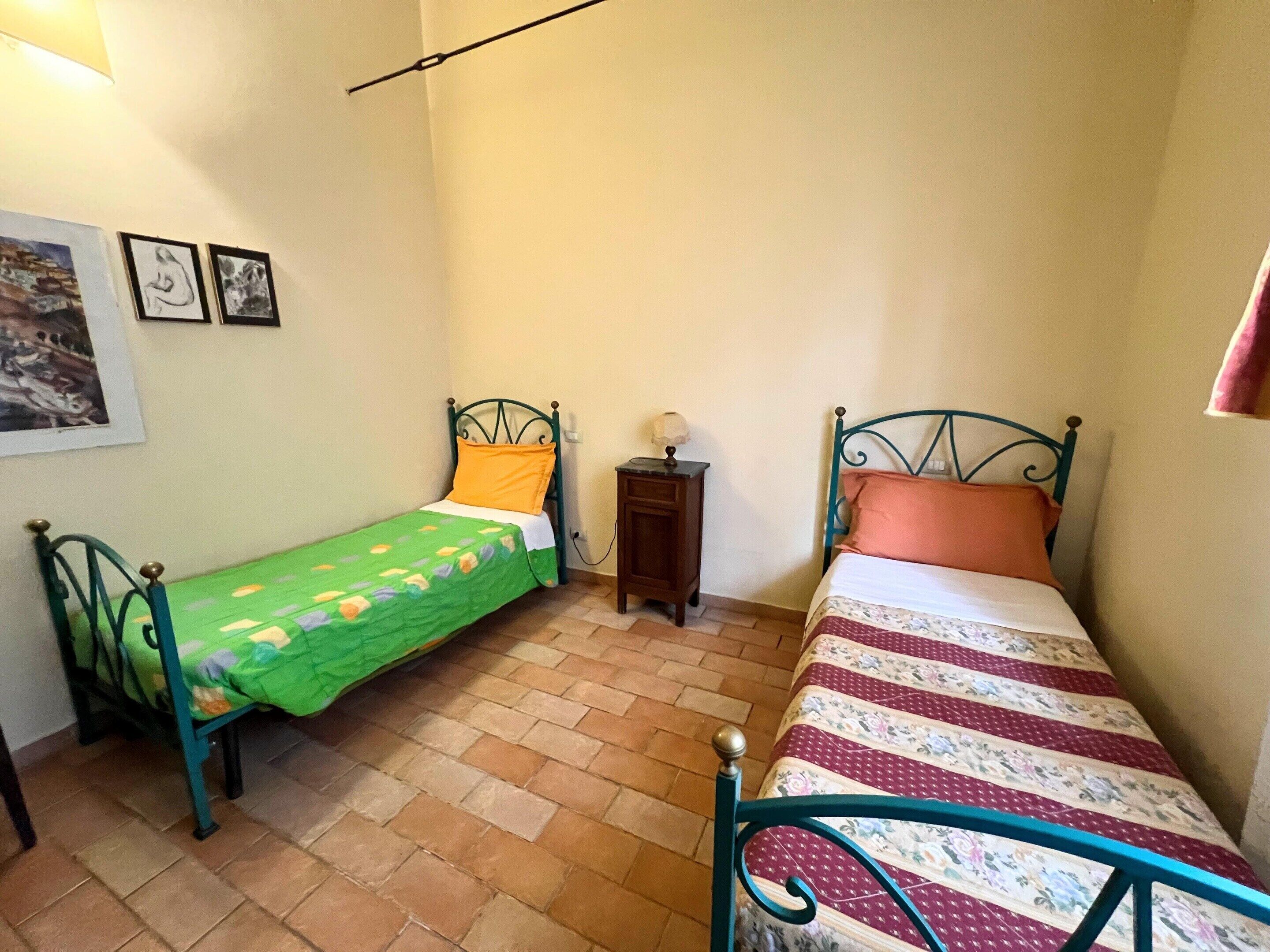 Un dormitorio pequeño con dos camas, una mesita de noche y un estante en la pared.