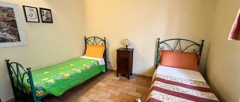 Un dormitorio pequeño con dos camas, una mesita de noche y un estante en la pared.