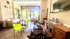 A dining area with a wooden table, chairs, and a TV mounted on the wall. - Berkah Syariah (Kutoarjo)
