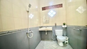 A bathroom with a shower, toilet, sink, and a small potted plant. - Berkah Syariah (Kutoarjo)