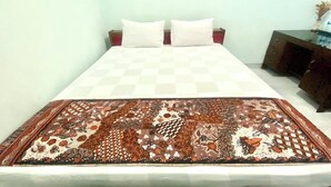 A bed with a checkered bedspread and a patterned throw blanket. - Berkah Syariah (Kutoarjo)