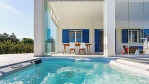 Ein moderner Poolbereich im Freien mit einer verglasten Terrasse, einem Tisch und Stühlen.