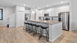 A modern kitchen with white cabinets, stainless steel appliances, and a central island with bar stools.