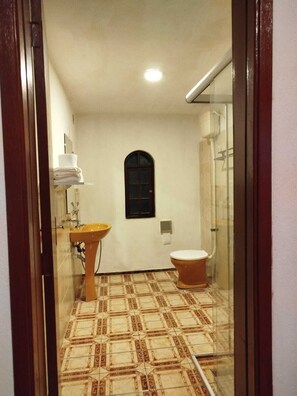 Ein Badezimmer mit gefliestem Boden, einem Waschbecken, einer Toilette und einer Duschkabine.