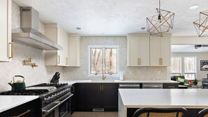 Une cuisine moderne avec des meubles noirs, un plan de travail blanc et un grand îlot central.