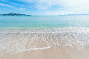A beach with clear turquoise water, gentle waves, and a distant mountain range. - Can Rovet - House With Private Pool. Free Wifi (Alcúdia)