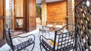 A patio with wicker furniture, a stone wall, and a wooden gate. - La Corte del Gallo by Interhome (Budoni)