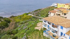 Een gebouw aan de kust met een pannendak, een balkon en uitzicht op zee.