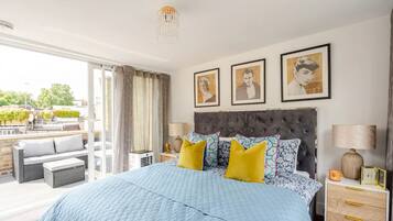 A bedroom with a large bed, a balcony, and a city view.