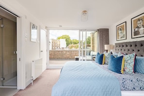 Een slaapkamer met een groot bed, een schuifdeur naar een balkon en uitzicht op de stad.