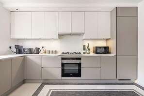 A modern kitchen with a built-in oven, a microwave, and a gas stove. - Extravagant 6 Bedroom Mansion by Mayfair London (London)