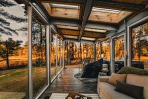 Un interior moderno con ventanas amplias, techo de madera y un rincón de descanso acogedor.
