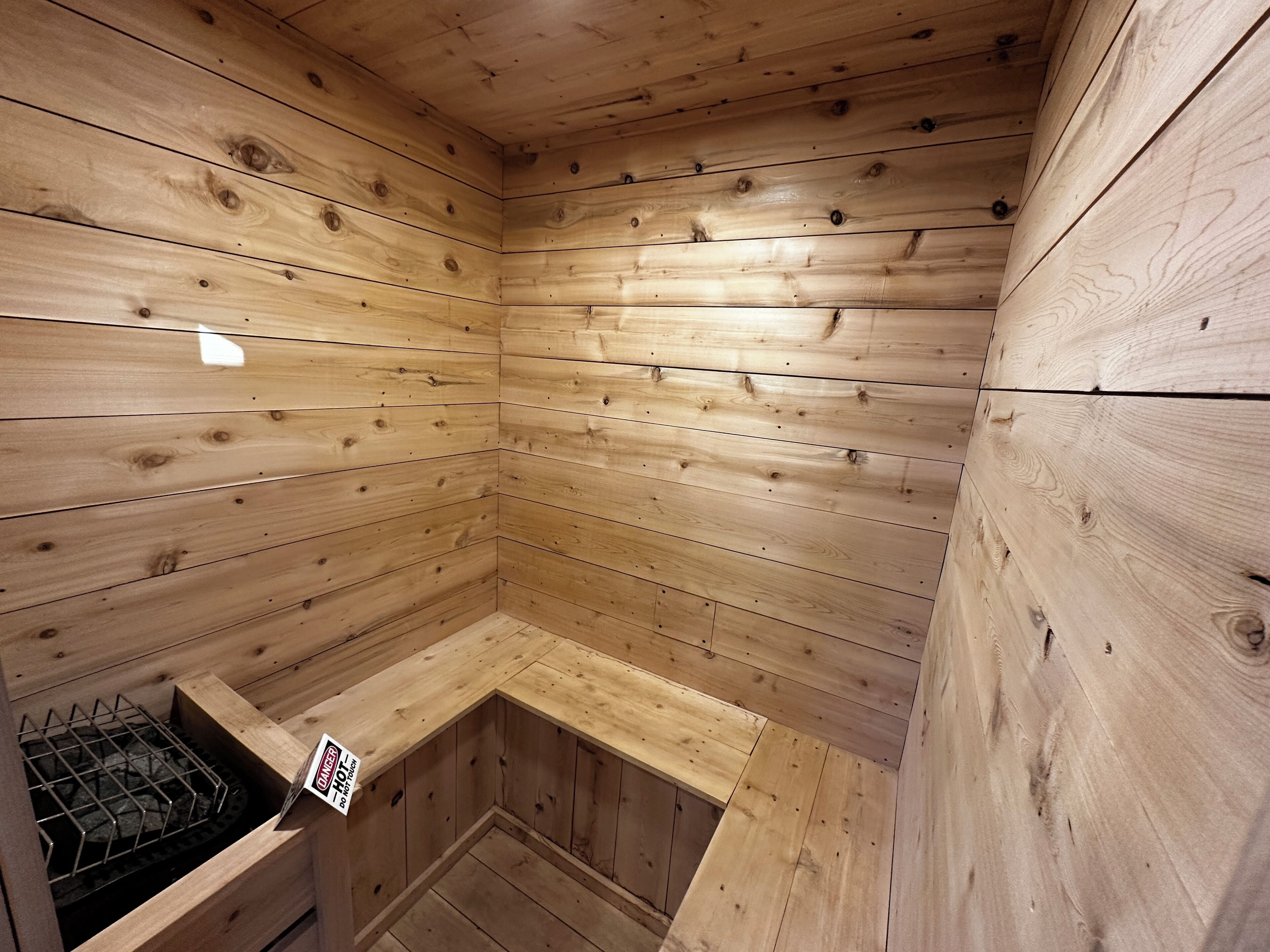 Una sauna de madera con un banco y un letrero de precaución.
