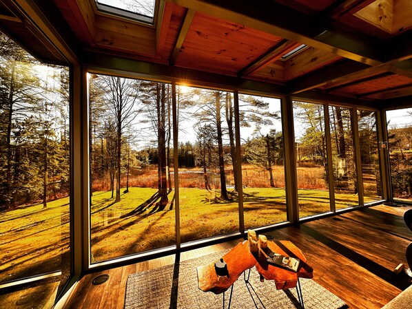 A room with large windows offering a view of a forested area.