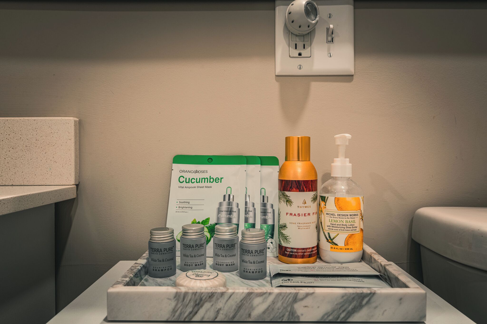 Ein Badezimmer-Waschtisch mit verschiedenen Pflegeprodukten, darunter eine Gurken-Gesichtsmaske, Duschgel und eine Zitronen-Basilikum-Körperlotion.