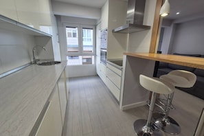 A modern kitchen with a stainless steel sink, a built-in oven, and a window with a view.