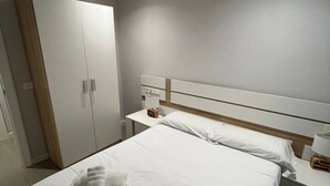 A hotel room with a bed, a nightstand, a wardrobe, and a bedside table. - 124C Apartamento moderno 2 dormitorios (Gijón)